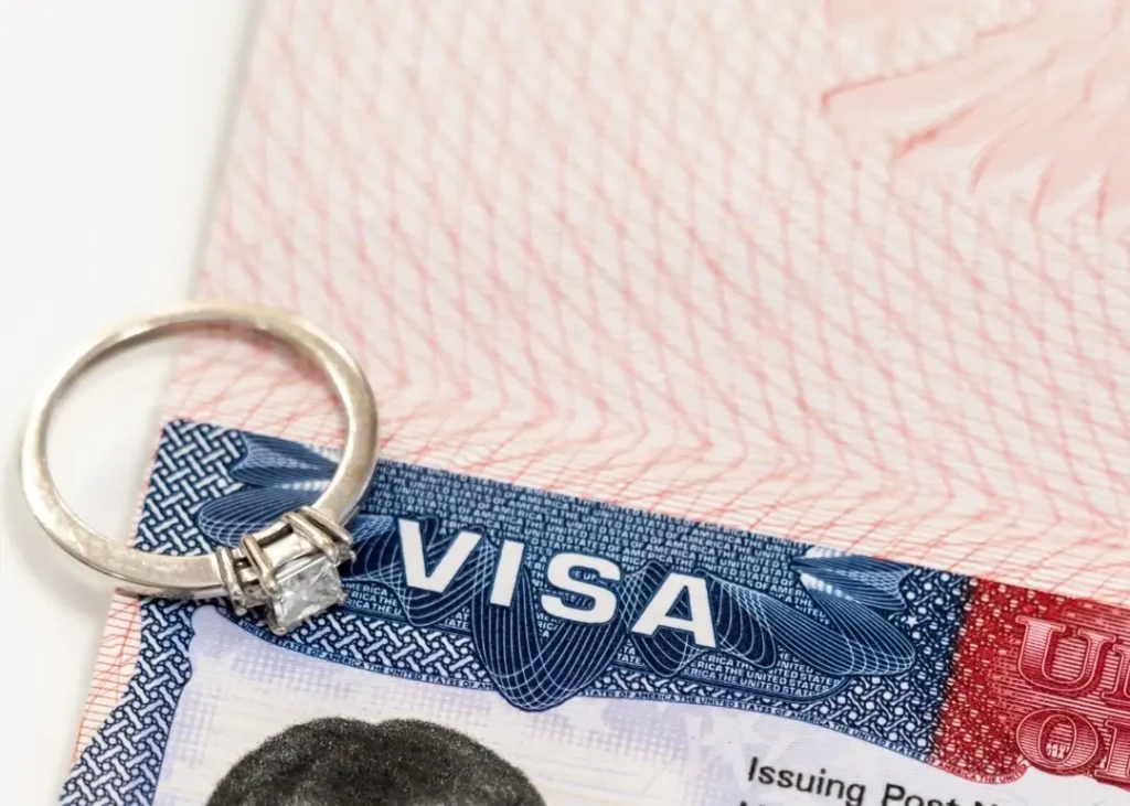 visa stamp on passport with engagement ring on top to make reference to the K1 fiance visa