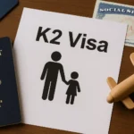 A flat lay image featuring a K2 visa document with an icon of an adult and child holding hands, symbolizing dependent immigration. Surrounding items include a U.S. passport, a Social Security card, and a wooden toy airplane, all set on a wooden surface.