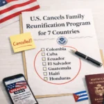 Horizontal photo-style illustration of a light wooden desk with a printed notice that reads “U.S. Cancels Family Reunification Program for 7 Countries.” Below the headline there is a checklist with the countries Colombia, Cuba, Ecuador, El Salvador, Guatemala, Haiti and Honduras, circled in red, with a black pen resting beside it. A yellow sticky note says “Cancelled!”, a smartphone shows a “Breaking News – Family Reunification Program Canceled for 7 Countries” alert, and several passports and small flags from affected countries sit near a corner of the U.S. flag, symbolizing the impact on immigrant families
